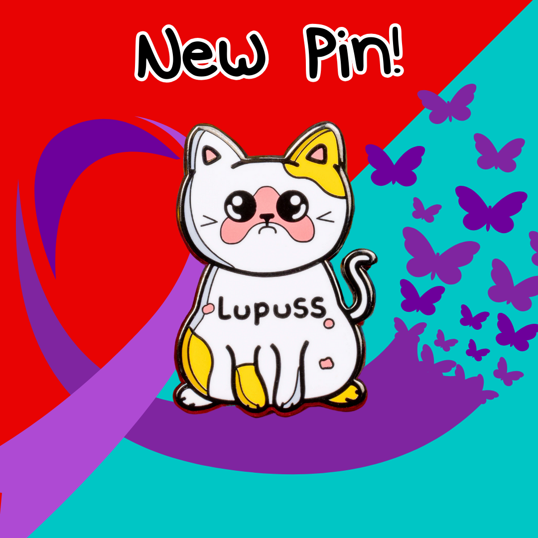 The cat shape enamel pin is orange and white with a sad expression, pink patches all over and black text across its middle reading 'lupuss'. The hand drawn design is raising awareness for lupus.