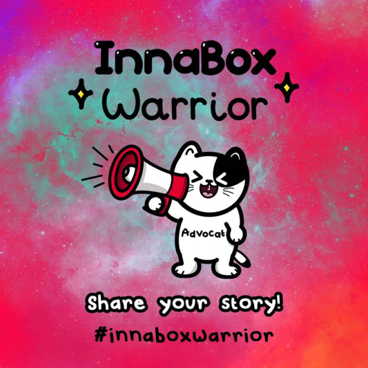 Illustration of a black and white cat holding a megaphone, shouting. The background is a colourful cosmic-style gradient. Text reads "InnaBox Warrior - Share your story! #innaboxwarrior" with sparkles around the title.