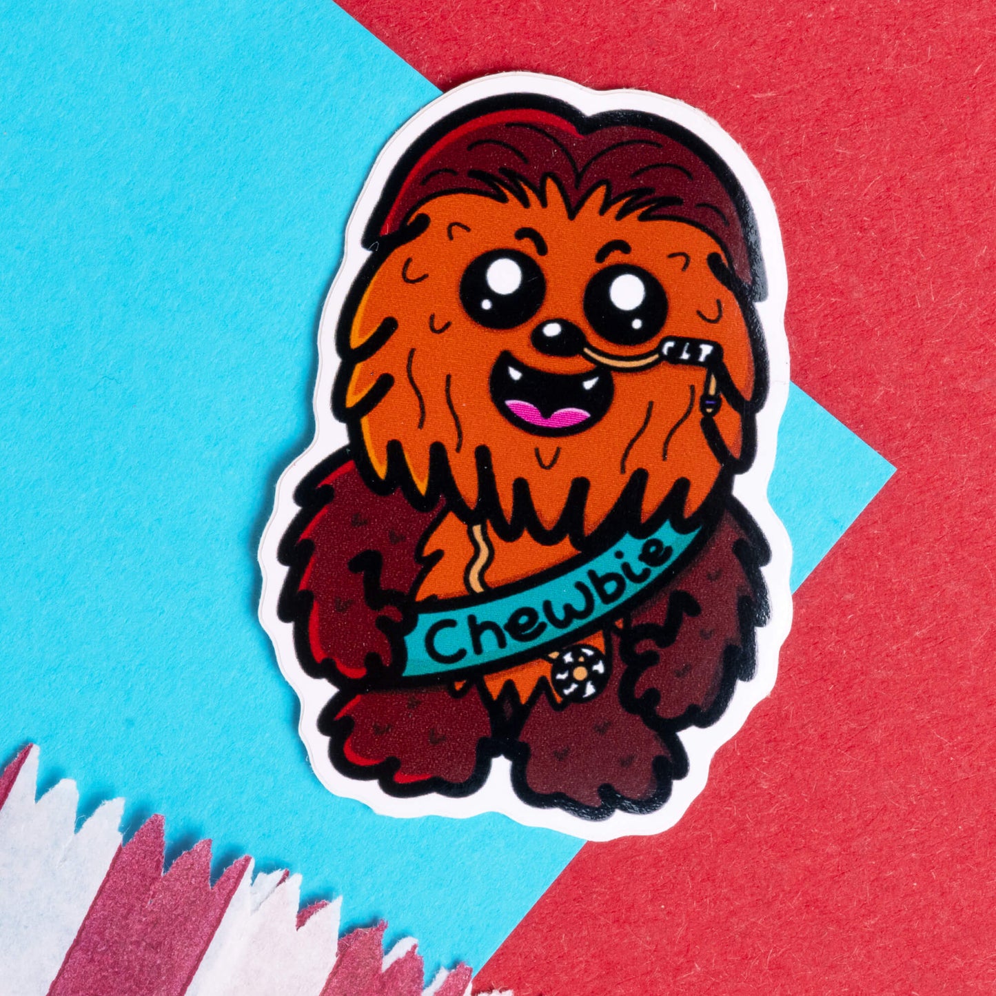 Innabox sticker featuring a cute cartoon character inspired by Chewbacca named Chewbie. The sticker shows Chewbie with a feeding tube, designed for those with chronic illnesses or hidden disabilities. The background includes a mix of vibrant blue, red, and white colours, reflecting Innabox’s mission to uplift those with disabilities through fun, disability-inspired designs.