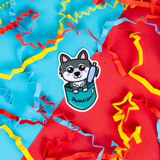 Innabox sticker featuring a cartoon wolf peeking out of a teal pocket with the word 'Dwolfism' written on it. The wolf has blushing cheeks, a playful expression. Surrounded by vibrant red, blue, and yellow paper confetti, this cheerful design by Innabox was created to raise awareness for dwarfism