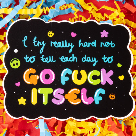 A sticker with a black background and wavy edges, featuring the text "I try really hard not to tell each day to GO FUCK ITSELF" in colorful letters. The text is surrounded by small heart, star, and smiley face icons. The sticker is placed on a background of colorful shredded paper in yellow, blue, and red. Hand drawn design created to raise awareness for chronic and invisible illnesses.